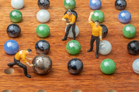 game concept with miniature human figures and colored marble ballsの写真素材