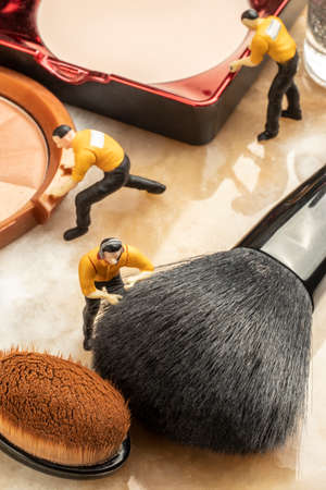 cosmetics concept with miniature human figures working on makeupの写真素材