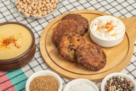 Presentation of Lebanese cuisine with delicious chickpea patties falafel and sauce on wooden plate at dining tableの写真素材