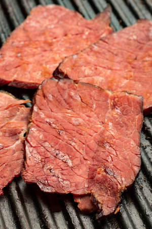 close-up of fried red meat slices on the grill