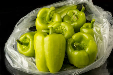close-up fresh green pepper in transparent bag on black backgroundの写真素材
