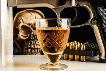 high alcohol drink whiskey background lead bullets pistol and skull drink concept in crystal goblet...
