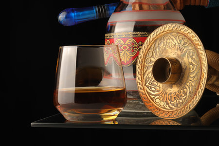 close-up black background decorative hookah set and glass of high alcohol whiskey