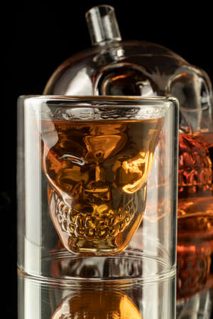 close-up black background high alcohol whiskey filled Transparent glass decanter carafe skull shot glass alcohol setの写真素材