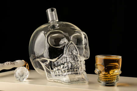 close-up black background high alcohol whiskey filled Transparent glass decanter carafe skull shot glass alcohol setの写真素材
