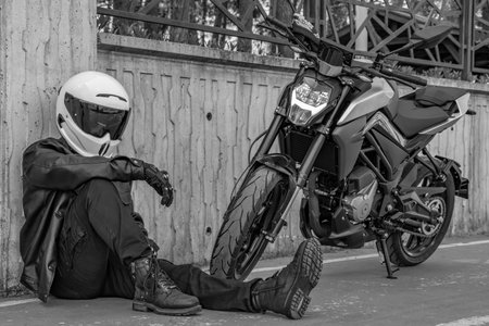 Detail view of portrait handsome male helmeted driver standing and driving on motorcycle outdoor