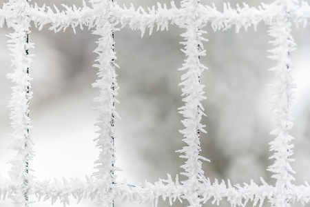 Three frozen snow, ice crystals windows in fenceの写真素材