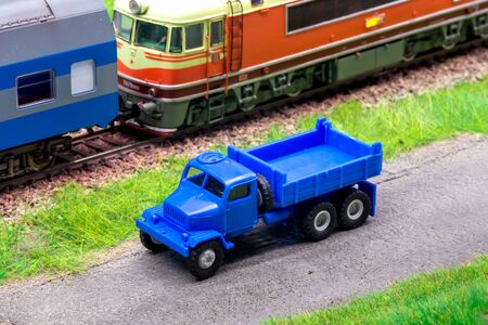 Blue scale truck on model train railroad layout road near trainの写真素材