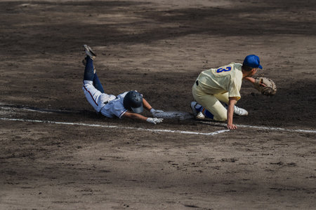 Baseball players in action during a game at a local baseball game.の写真素材