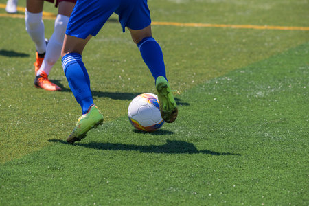 Soccer player in action with ball on field, closeup of photoの写真素材