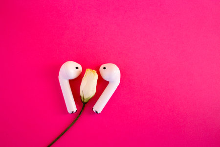 Wireless white headphones on a pink background, space for text
