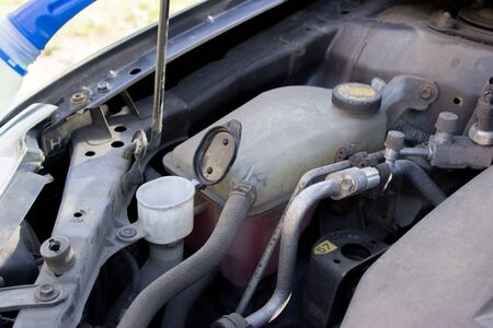 male hand pours liquid into the washer under the hood of a carの写真素材