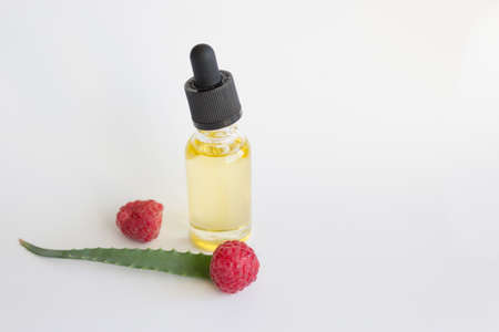 Dropper bottle of aloe vera essential oil and ripe raspberries, black disposable razorの写真素材