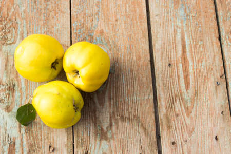 Fruit apple quince with a branch of green leaves on a wooden background.の写真素材