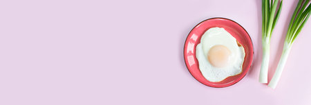 Sunny side up egg banner. Fried eggs with green onions on a pink background.