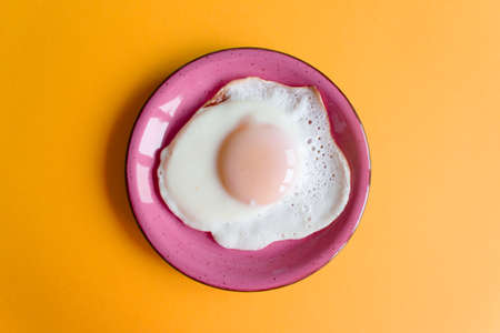 Plate with delicious sunny side up egg on color backgroundの写真素材