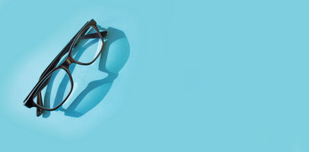 Glasses with a black frame on a blue background. Vision concept.