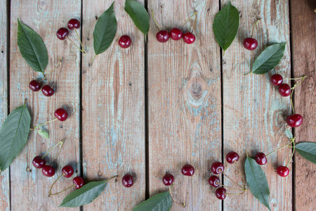 Cherry berry. Harvest cherries on a wooden background. Ripe cherry with green leaves top view