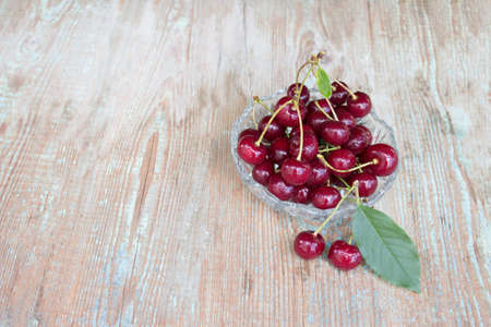Ripe cherries, cherries in a plate on a wooden background with copy space. Cherry berry.の写真素材