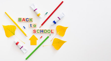 Back to school concept. Colourful pencils, tubes of paints and words "back to school" on white background flat lay with copy space.の写真素材