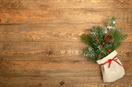 Christmas background. Green Christmas tree branches and pine cone in canvas pouch on wooden rustic background flat lay. Copy spaceの写真素材