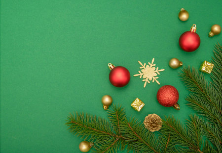 Golden and red Christmas ornaments and green Christmas tree branches on green background. Copy spaceの写真素材