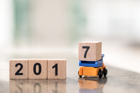2017 year concept. Truck toy carrying number 7 wooden block and loading to 2 0 1 number block row.の写真素材
