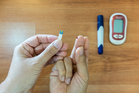 Medicine, diabetes, glycemia, health care and people concept - close up of man hands checking blood sugar level by Glucose meterの写真素材