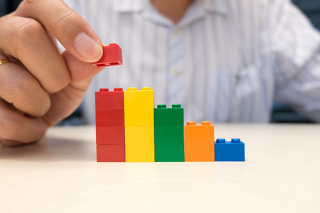 Businessman hand placing red plastic block on the top of stair. Business growth conceptの写真素材