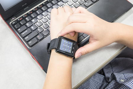 Young woman using her modern smart watches with laptop computerの写真素材