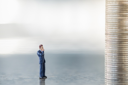 Money, Financial, Business Growth concept, Businessman miniature figures standing, looking and thinking to stack of coins on right side.の写真素材
