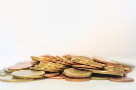 Closup of pile of gold and copper coins on white ground.