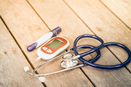 Glucose meter with lancet and stethoscope on wooden table use for Medicine, diabetes, glycemia, health care and people concept.の写真素材