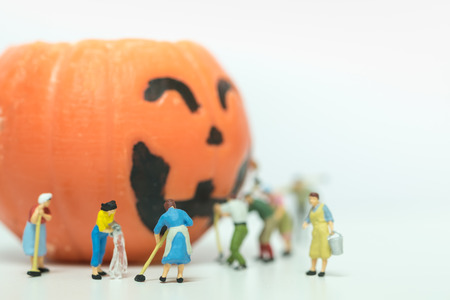 Halloween Concept. Group of worker and cleaner miniature figures working cleaning and wash on pumpkin ghost head wax candle to prepare the halloween nigt and party.の写真素材