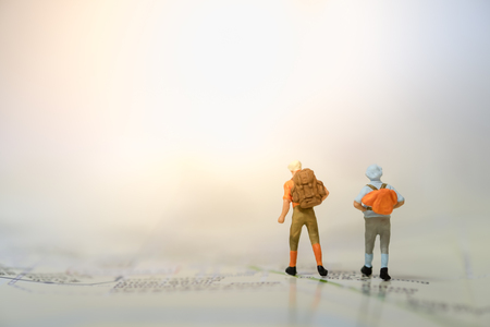 Travelling concepts. Two of miniature people mini figures with backpack standing on mapの写真素材