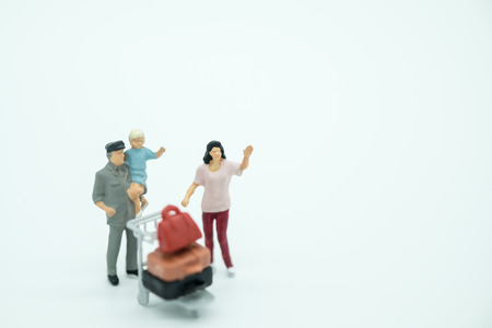 Travel and Family concept. Man, woman and child miniature people figures with luggage airport cart on white backgroundの写真素材