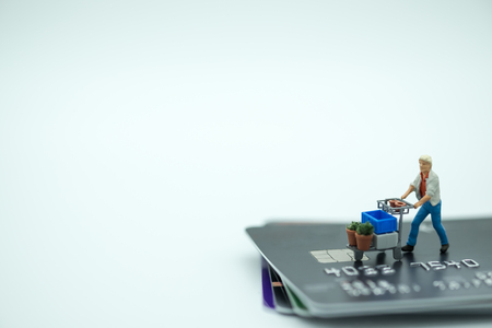 Shopping and e-commerce concept. Man with shopping cart toy miniature figure   on stack of credit cards with copy spaceの写真素材