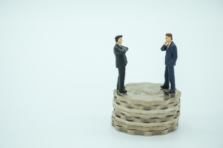 Money, Business and competition concpet. Two businessman miniature people figures standing face to face on stack of 2 Hong Kong dollars coinsの写真素材