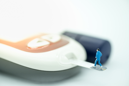 Close up of runner miniature figure running on blood sugar test strip and connect to Glucose meter with lancet. - use for Medicine, diabetes, glycemia, sport, health care and people concept.の写真素材