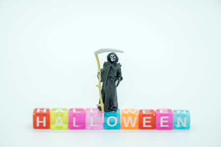 Halloween Concept. Death miniature figure standing on colorful plastic alphabet block.
