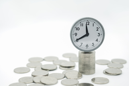 Money saving and time concept. Vintage round watch on pile and stack of silver coins.の写真素材