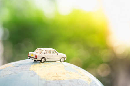 Travel and transport concept. Miniature Toy car on world map balloon with green nature as background.の写真素材