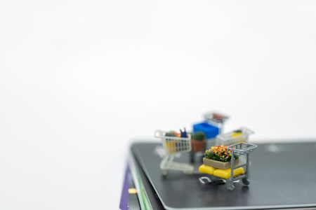Shopping and e-commerce concept. Close up of four miniature shopping carts toy figures on stack of credit cards with copy spaceの写真素材