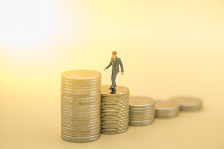 Business saving concept. Businessman miniature figure walking on top of stack of silver coins.の写真素材