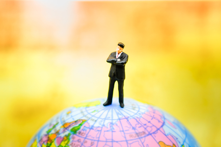 Global and Business Concept. Businessman miniature people figure standing on mini world ball model.の写真素材