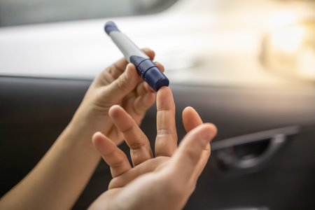 Close up of woman hands using lancet on finger to check blood sugar level by Glucose meter in the...