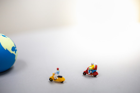 Travel Concept. Group of traveler miniature figures ride motorcycle / scooter to the mini world ball.の写真素材