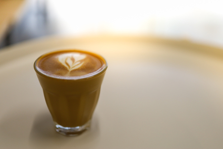 Close up of shot glass of hot coffee latte with heart shape art.の写真素材