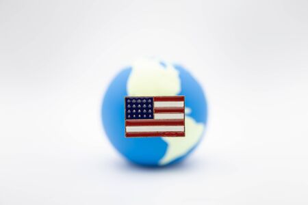 Close up of United State of America pin national flag over mini world ball on white background.の写真素材