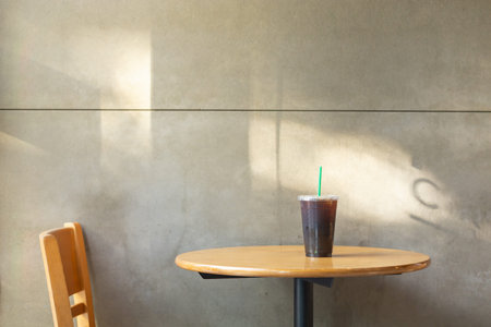 Take away plastic cup of iced black coffee Americano on wooden table in the restuarant